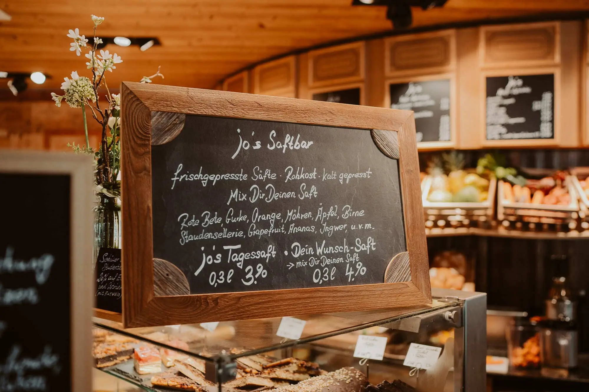 Kreidetafel der Saftbar vor der Kuchentheke